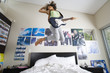 Photo: Teenage girl (16-18) playing electric guitar, jumping in air above bed, low angle view Teenage girl (16-18) playing electric guitar, jumping in air above bed, low angle view