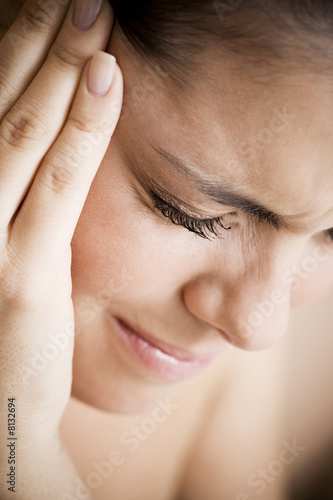 Photo: Woman with toothache or headache, holding her hand to her temple Woman with toothache or headache, holding her hand to her temple