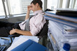 Photo: Young businessman slouching in chair by paperwork on desk, head in hand, side view Young businessman slouching in chair by paperwork on desk, head in hand, side view