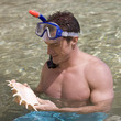 A male snorkeler holding a shell