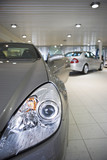 Photo: New silver saloon and convertible cars parked in large showroom, focus on foreground New silver saloon and convertible cars parked in large showroom, focus on foreground