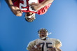 Photo: American football player running with ball at opposing player during competitive game, upward view American football player running with ball at opposing player during competitive game, upward view