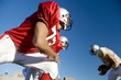 Photo: American football player running with ball at opposing team during competitive game, side view, low angle view American football player running with ball at opposing team during competitive game, side view, low angle view