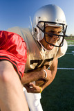 Photo: Determined American football player running with ball during competitive game, opposing player attempting tackle, close-up Determined American football player running with ball during competitive game, opposing player attempting tackle, close-up