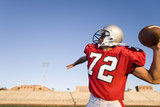 Photo: American football quarterback, in red strip, about to throw ball during competitive game, profile American football quarterback, in red strip, about to throw ball during competitive game, profile