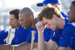 Photo: Dejected baseball team, in blue uniform, sitting on bench in stand during competitive baseball game, side view (differential focus) Dejected baseball team, in blue uniform, sitting on bench in stand during competitive baseball game, side view (differential focus)