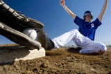 Photo: Baseball player, in blue uniform, sliding into base on pitch during competitive game, opposing player holding ball in foreground (surface level, blurred motion) Baseball player, in blue uniform, sliding into base on pitch during competitive game, opposing player holding ball in foreground (surface level, blurred motion)