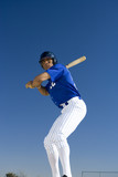 Photo: Baseball batter standing against clear blue sky, preparing to hit ball, front view, low angle view Baseball batter standing against clear blue sky, preparing to hit ball, front view, low angle view