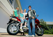 Photo: Family posing beside red motorbike on driveway, smiling, side view, portrait (surface level) Family posing beside red motorbike on driveway, smiling, side view, portrait (surface level)