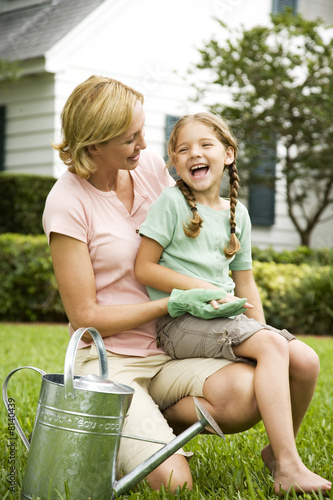 Photo: girl sitting on mother's lap laughing in the garden girl sitting on mother's lap laughing in the garden