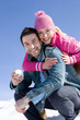 Young couple embracing in snow, man holding snow ball, smiling, portrait