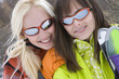 Photo: Two young women with skis in snow, wearing sunglasses, smiling, portrait, close-up Two young women with skis in snow, wearing sunglasses, smiling, portrait, close-up