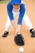 Boy stooping to pick up baseball
