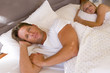Young couple lying in bed beneath covers, smiling, portrait, elevated view