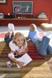 Boy and girl (6-8) on rug in front of television, portrait of girl smiling with book and mp3 player, elevated view