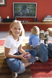 Photo: Boy and girl (6-8) on rug in front of television, portrait of girl smiling and using mp3 player Boy and girl (6-8) on rug in front of television, portrait of girl smiling and using mp3 player