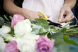 Woman's hands tying together a bouquet of pink and white roses