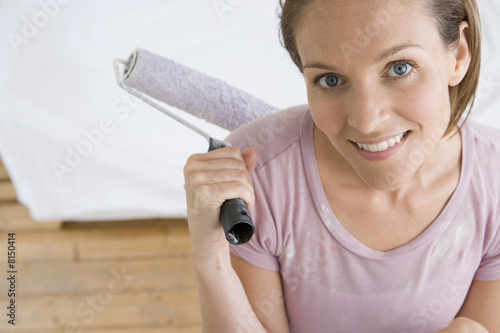 Photo: Young woman with paint roller, smiling, portrait, elevated view Young woman with paint roller, smiling, portrait, elevated view