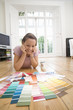 Photo: 20's woman lying on floor choosing paint colours from paint swatches in living room. 20's woman lying on floor choosing paint colours from paint swatches in living room.