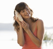 A woman holding a shell to her ear