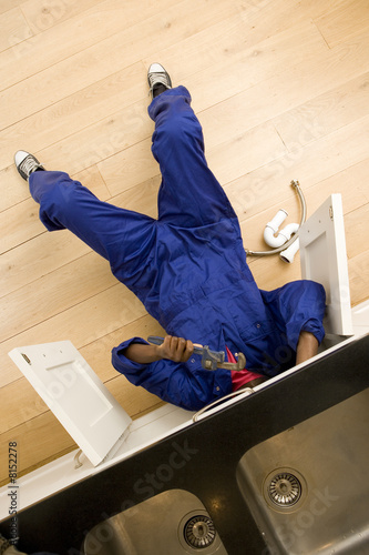 Plumber working under kitchen sink, overhead view