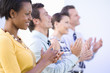 Businessmen and women in row clapping and smiling, close-up, side view