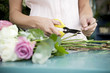 Woman's hands tying together a bouquet of pink and white roses