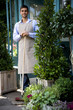 Male florist standing with a  broom outside his shop