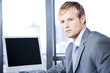 Businessman next to a computer screen on a modern office