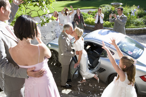 Photo: 60's couple celebrating marriage next to car surrounded by family throwing petals. 60's couple celebrating marriage next to car surrounded by family throwing petals.