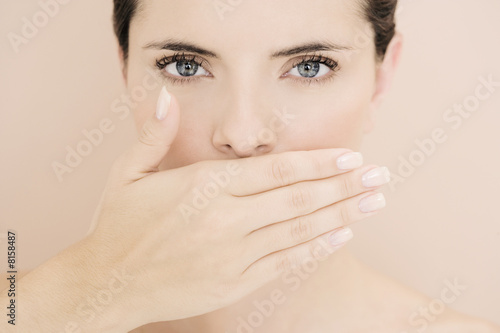 Photo: Young woman with hand over her mouth, speak no evil Young woman with hand over her mouth, speak no evil