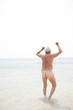 Naked senior man running into the sea