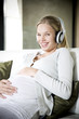 Pregnant woman laughing whilst listening to music on headphones