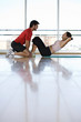 Man helping woman with sit-ups in gym studio, side view