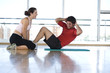 Woman helping man with sit-ups in gym studio, side view