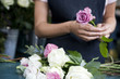 Woman florist creating a bouquet of pink and white roses