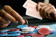 Woman placing ring on pile of gambling chips on table, mid section