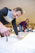 Man measuring bed in furniture shop, family in background, smiling