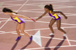 Female relay athletes passing baton (blurred motion)