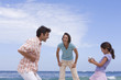Family of three on beach, daughter (6-8) with camcorder, low angle view