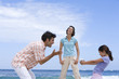 Family of three on beach, daughter (6-8) with camcorder, low angle view