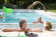 Photo: Family of four in swimming pool, boy (6-8) doing back flip into water, portrait of girl (8-10) smiling Family of four in swimming pool, boy (6-8) doing back flip into water, portrait of girl (8-10) smiling