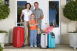 Photo: Family of three with lugguage by front door, smiling, portrait Family of three with lugguage by front door, smiling, portrait