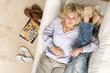 Photo: Young couple on sofa, woman embracing man's legs, smiling, portrait, elevated view Young couple on sofa, woman embracing man's legs, smiling, portrait, elevated view