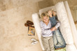 Photo: Young couple on sofa, woman embracing man's legs, smiling, portrait, elevated view Young couple on sofa, woman embracing man's legs, smiling, portrait, elevated view