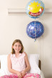 Girl (10-12) in hospital bed with 'Get Well' balloons, smiling, portrait