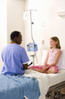 Doctor smiling at girl (10-12) in hospital bed