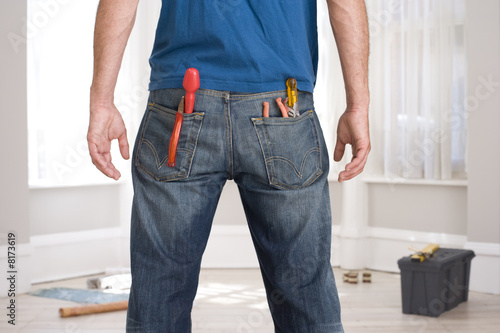 Photo: Man decorating, tools in pockets, rear view Man decorating, tools in pockets, rear view
