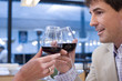 Couple proposing toast with wine glasses in restaurant, close-up