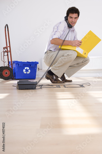 Photo: Businessman on telephone by recycling bin Businessman on telephone by recycling bin